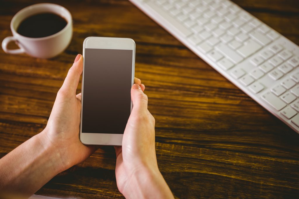 Woman using her smartphone on wooden table