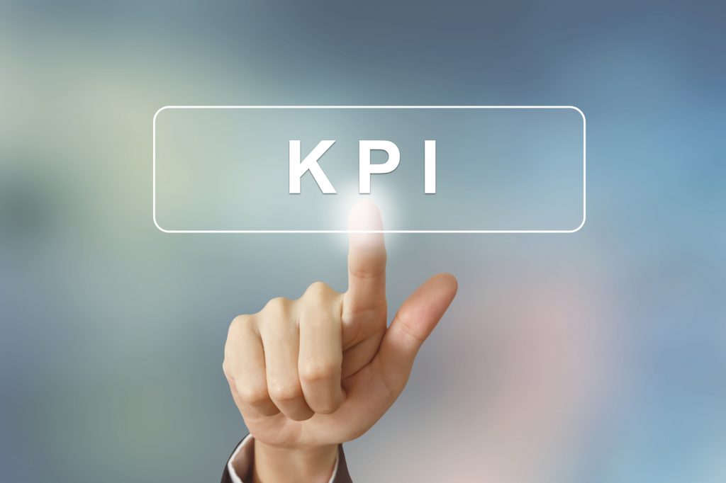 hand clicking KPI or Key Performance Indicator button on blurred