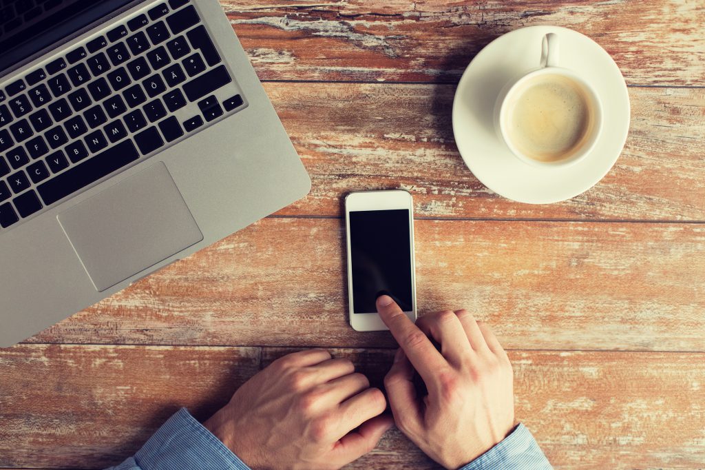 close up of hands with laptop and smartphone