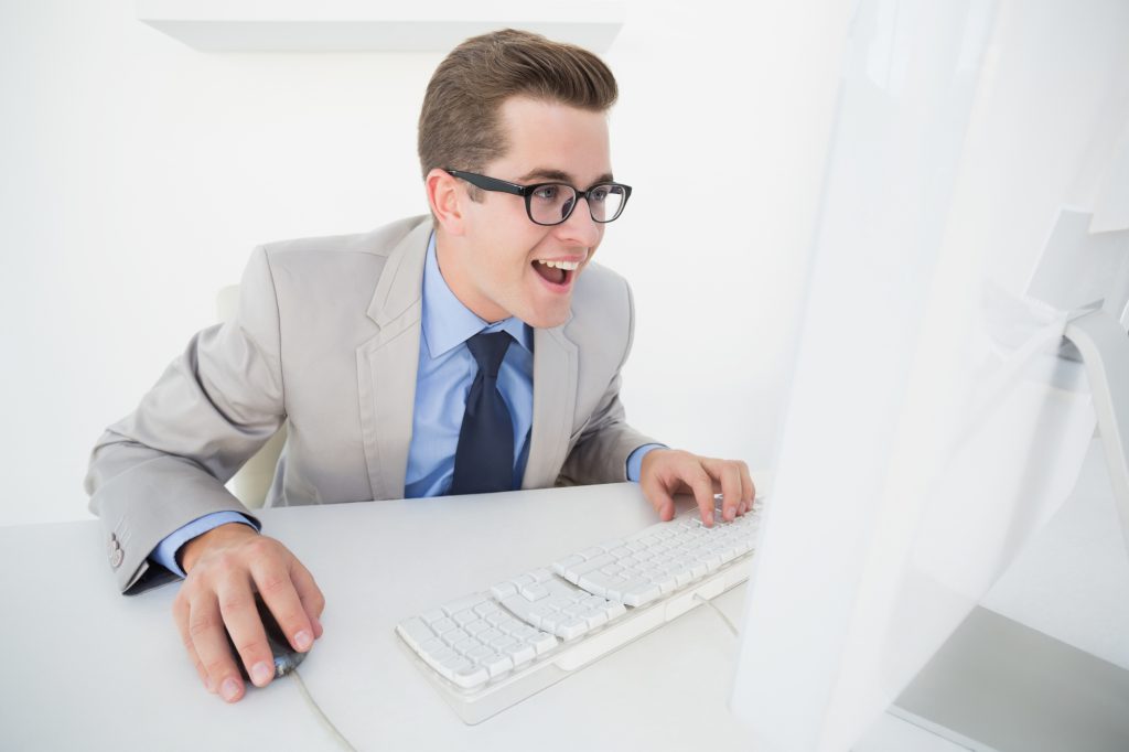 Excited businessman working on computer in his office